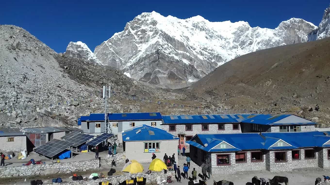 Buddha Lodge at Gorakshep with solar panels, tents, and snow-capped Himalayan mountains.
