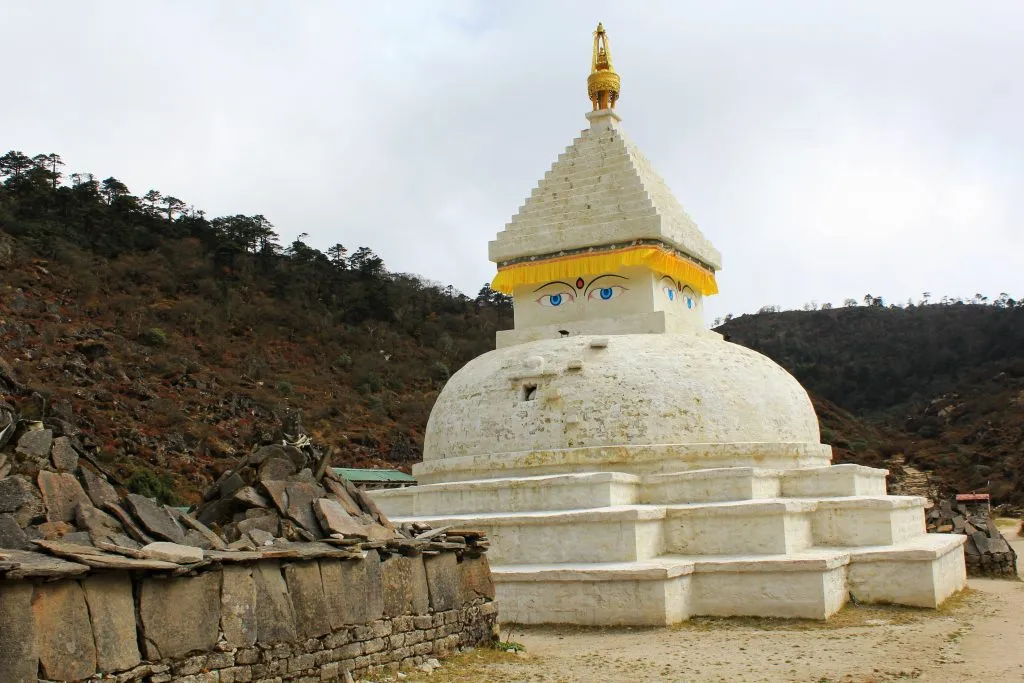 Tibetan buddhist stupa chorten shrine with buddha eyes and colorful prayer flags near khumjung village